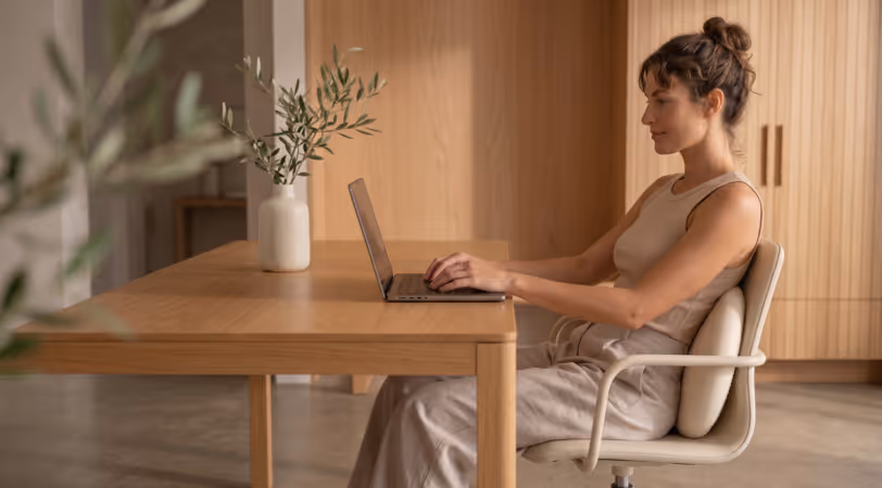 Employee working at her laptop with a BetterMe support cushion behind her back at a desk